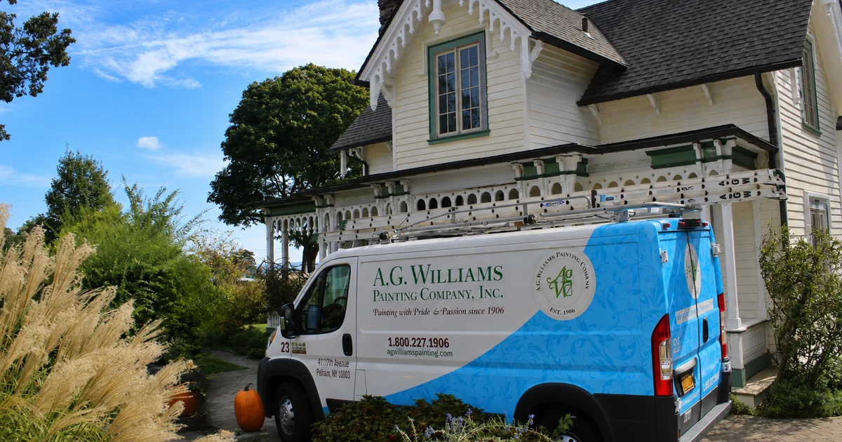 An A.G. Williams Painting Company van parked beside a light-yellow Victorian home with ornate white trim.