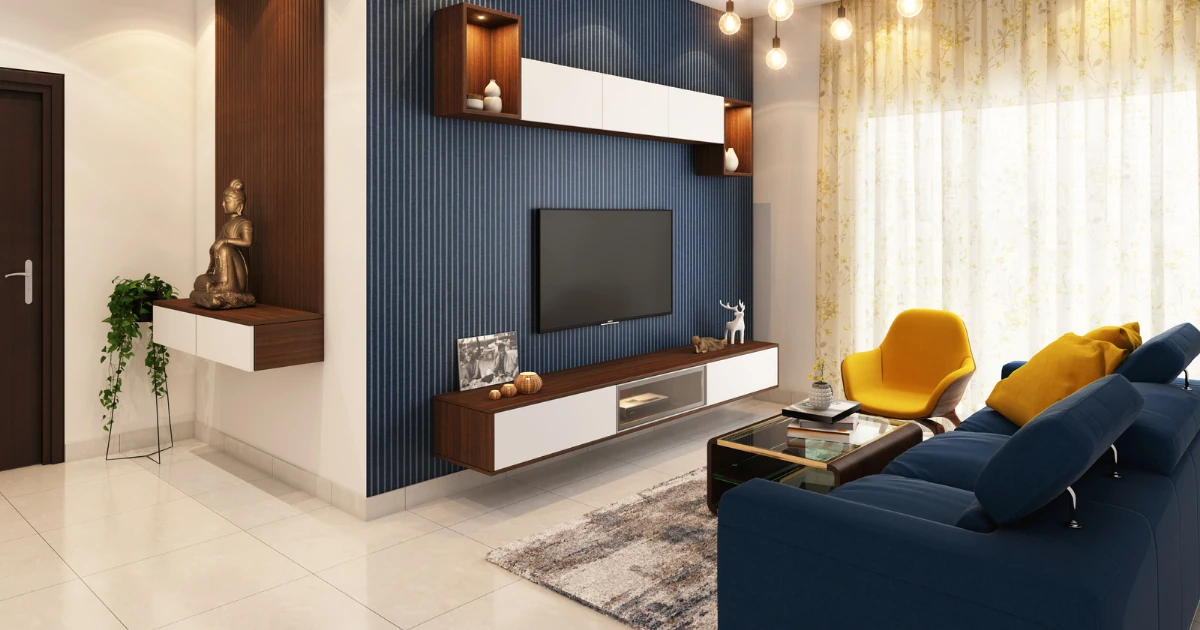 Living room with a dark blue vertically textured slat accent wall behind a mounted TV, floating wood shelving, a blue sofa, and a mustard-yellow accent chair.