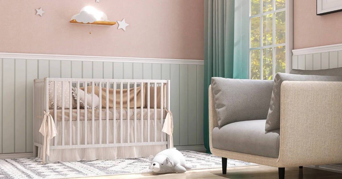 A pastel pink nursery with sage-green beadboard wainscoting below a white crib, gray armchair, and teal curtains beside a window.