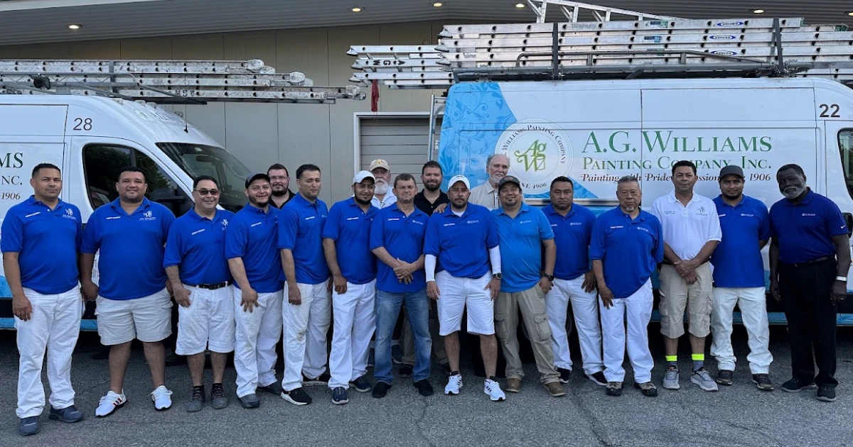 A.G. Williams Painting Company crew standing together in front of company vans and ladders.