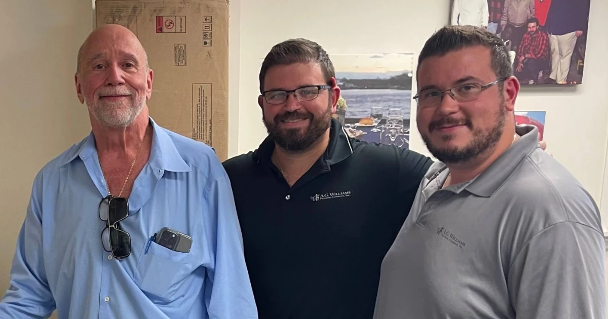 Three A.G. Williams Painting Company team members in branded company shirts at the company office.