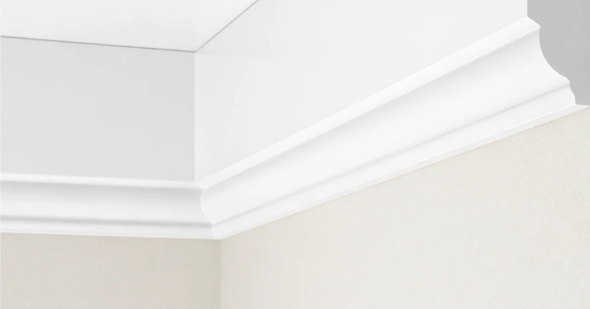 A streamlined white crown moulding profile running along the corner where a pale wall meets a white ceiling.