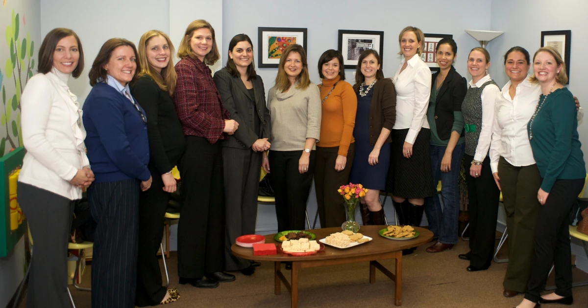 A large group of Junior League of Pelham volunteers gathered in the finished reception area with student artwork displayed on the freshly painted walls.