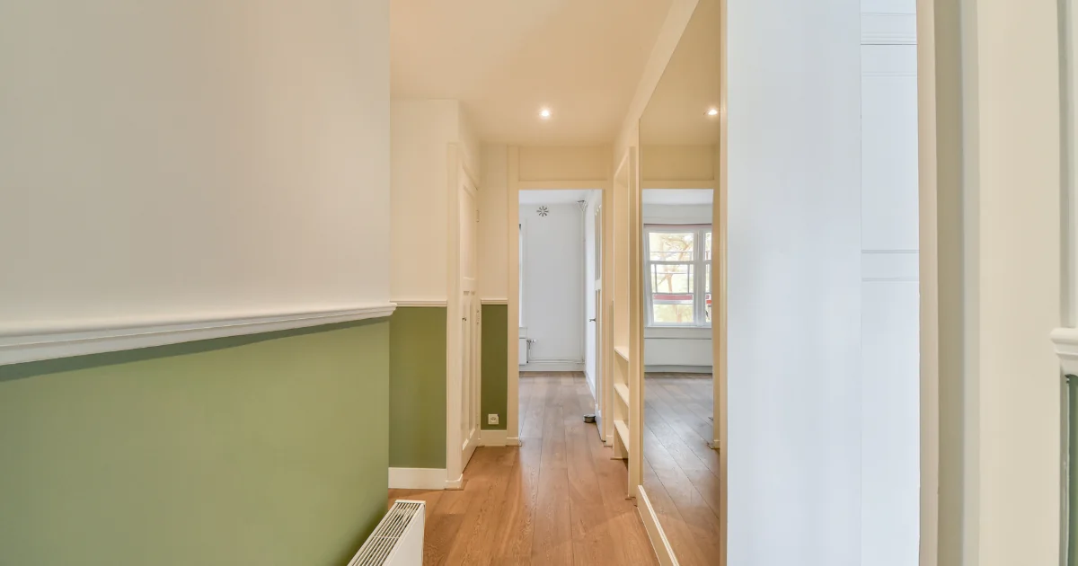 Hallway with white upper walls and muted green paint below the chair rail.