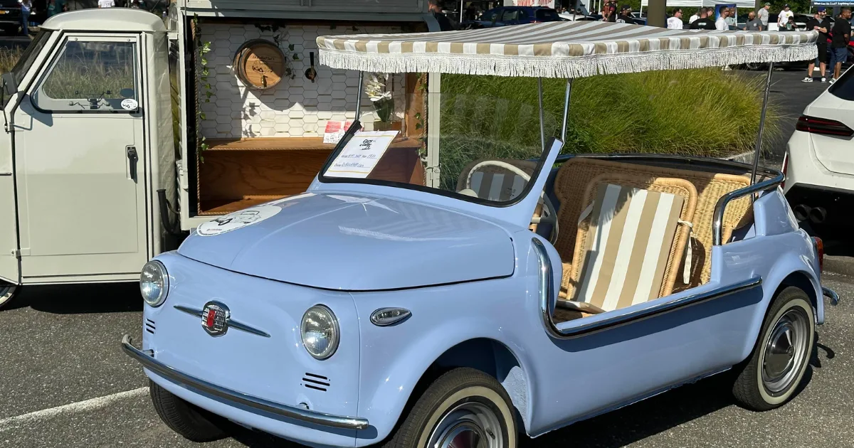 Light-blue vintage Fiat 500 Jolly with wicker seats and a striped canopy at Cars & Coffee.