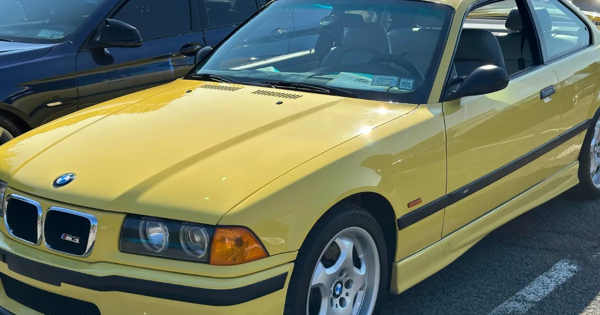 Yellow BMW M3 coupe gleaming in the sun at Cars & Coffee.