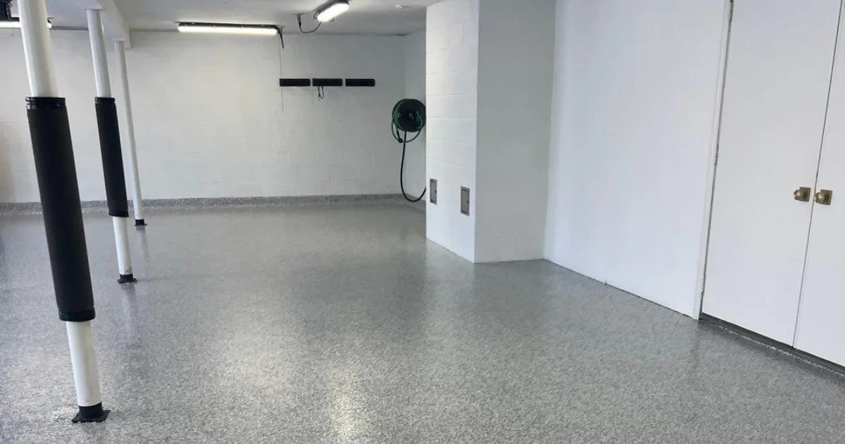 Finished light-gray flake floor coating across a clean basement with support columns.