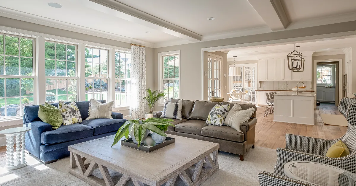 Blue and neutral seating zones in a sunlit open living room and kitchen.