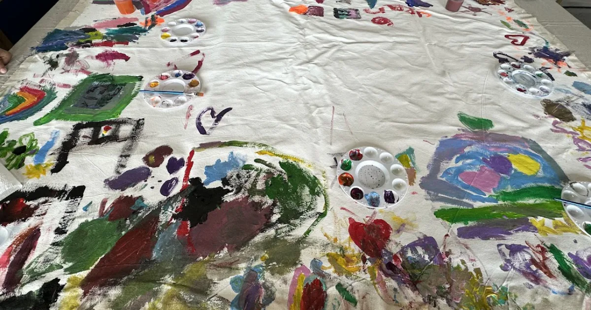 Children’s community mural in progress with colorful hand-painted shapes and designs.