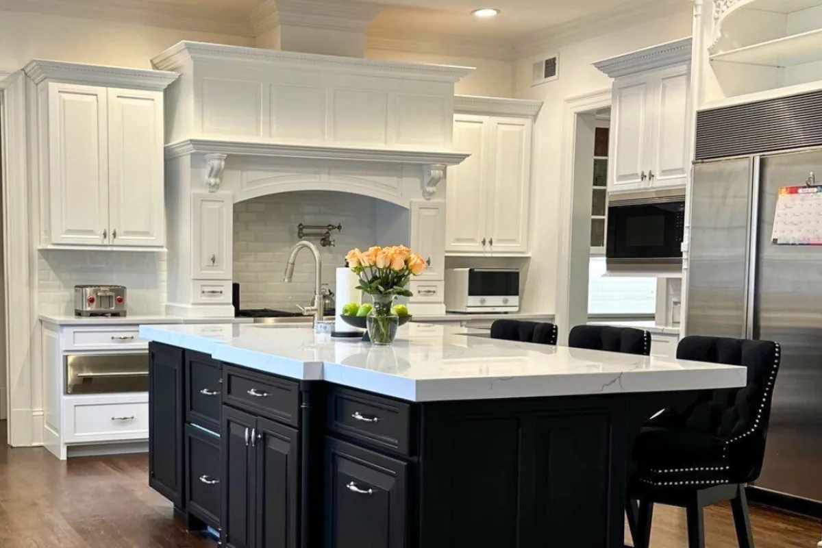 Finished white kitchen cabinets with a dark island after refinishing.