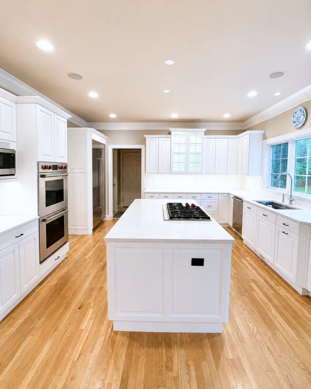 Finished Stamford kitchen with white cabinets, a white island, stainless steel appliances, and hardwood floors