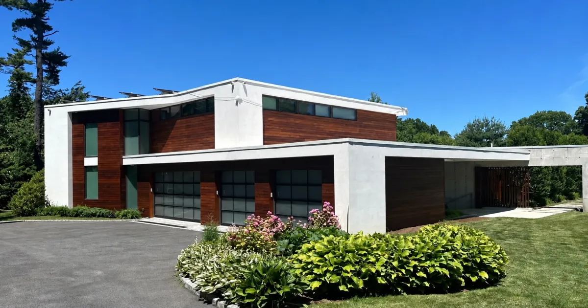 Finished modern home exterior with white stucco, warm wood siding, and black-framed windows