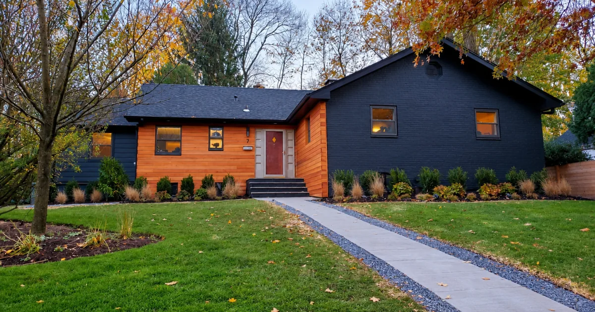 The same brick ranch after exterior painting in deep navy with natural cedar accents.
