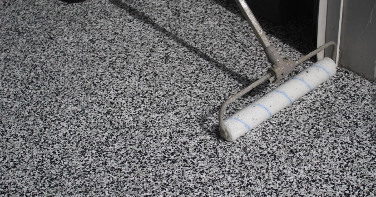 An A.G. Williams installer rolling a protective clear coat across a decorative flake floor.
