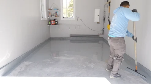 A.G. Williams installer applying the basecoat to a prepared residential concrete floor.