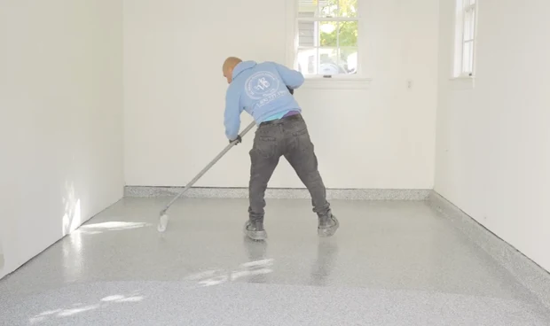 An A.G. Williams installer rolling a protective clear coat across a decorative-flake floor.