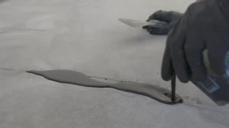 Concrete repair material being applied to a crack before floor coating installation.