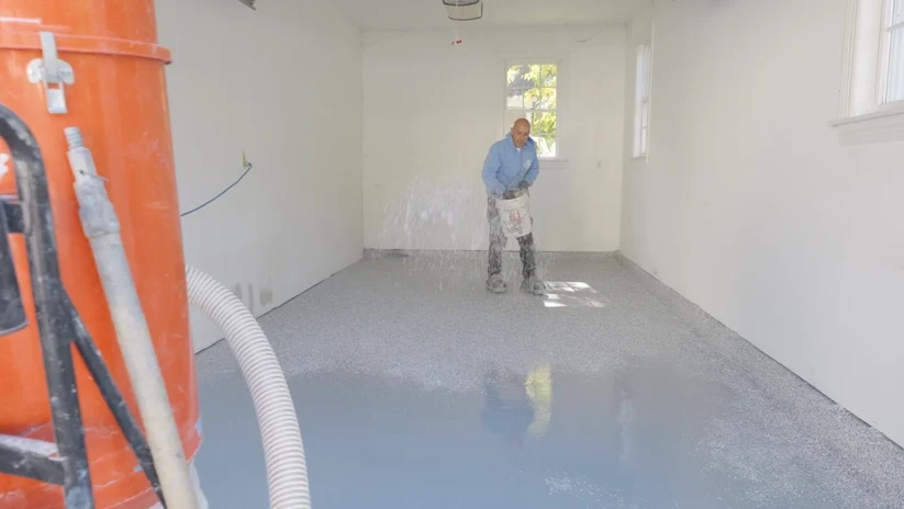 Decorative flakes being broadcast across a wet residential floor-coating basecoat.