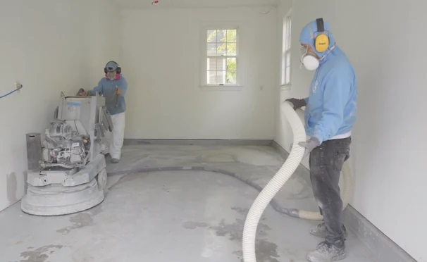 A.G. Williams crew members diamond grinding a residential concrete floor with vacuum-connected equipment.