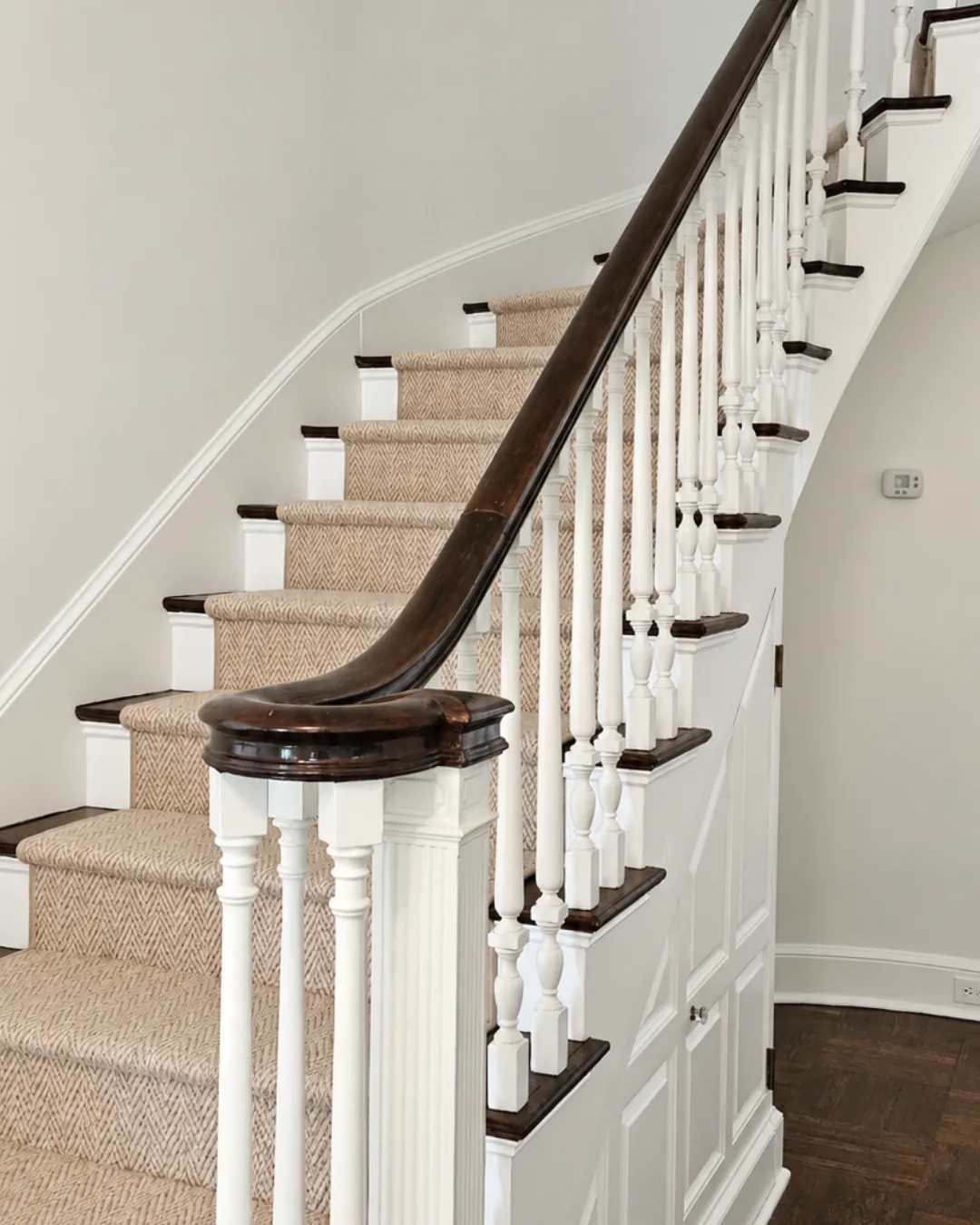 Painted white staircase with dark wood handrails and a patterned runner in New Canaan.